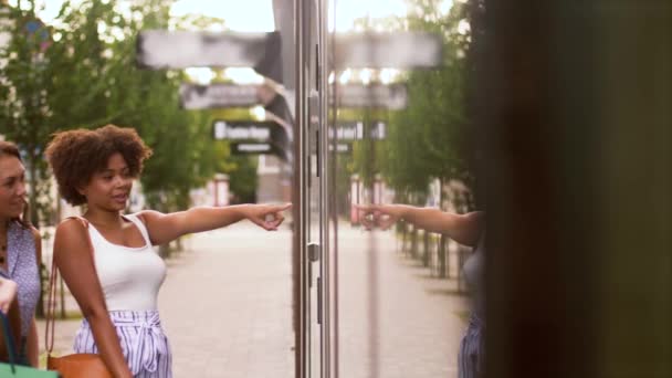 Frauen mit Einkaufstüten blicken in Schaufenster — Stockvideo