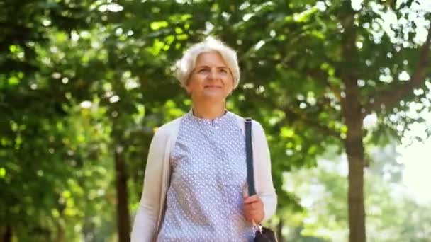Счастливая пожилая женщина, гуляющая по летнему парку — стоковое видео