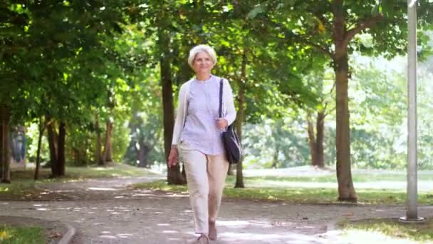 Feliz mujer mayor caminando a lo largo del parque de verano — Vídeos de Stock