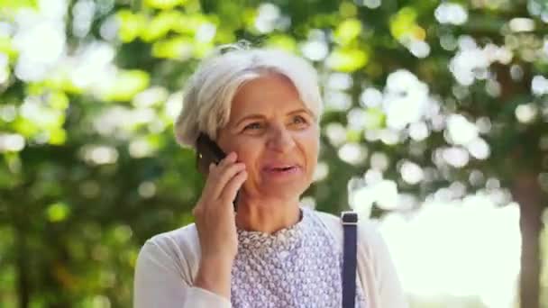 Старшая женщина звонит на смартфон в парке — стоковое видео