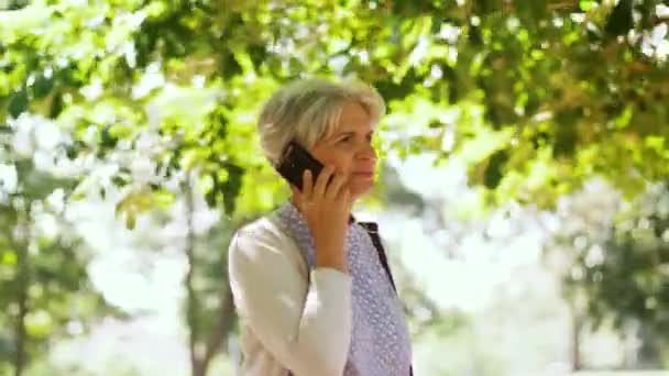 年配の女性が公園でスマート フォンで呼び出す — ストック動画