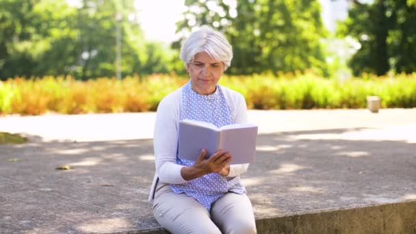 Senior vrouw lezing boek bij zomer park — Stockvideo