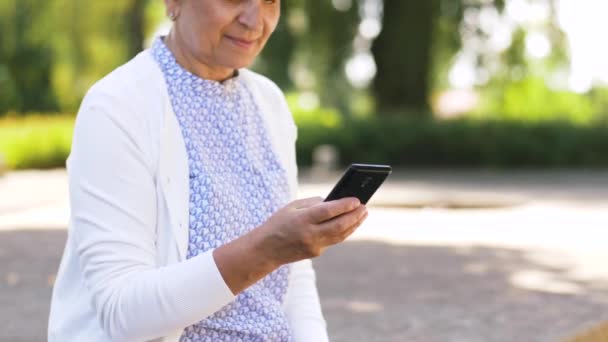 Donna anziana che chiama su smartphone nel parco — Video Stock