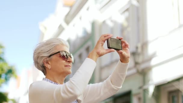 Пожилая женщина фотографирует на смартфоне в городе — стоковое видео