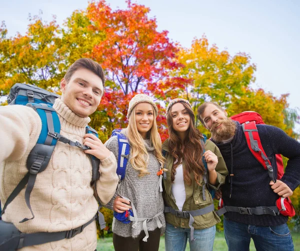 Amigos com mochilas tirando selfie no outono — Fotografia de Stock