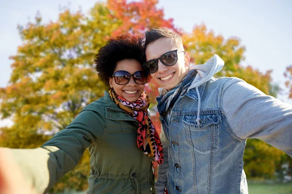 Feliz mixta pareja tomando selfie en otoño — Foto de Stock