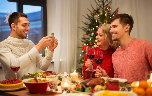 Happy friends photographing at christmas dinner — Stock Photo, Image