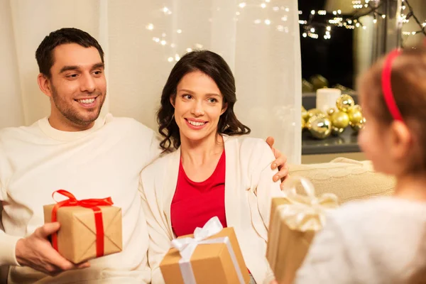 Glückliche Familie, die zu Hause Weihnachtsgeschenke verteilt — Stockfoto