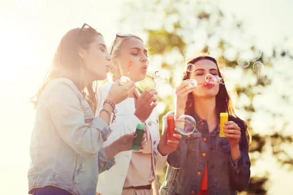 Unga kvinnor eller flickor blåser bubblor utomhus — Stockfoto