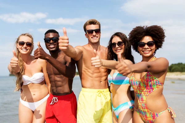 Glada vänner visar tummen upp på sommaren beach — Stockfoto