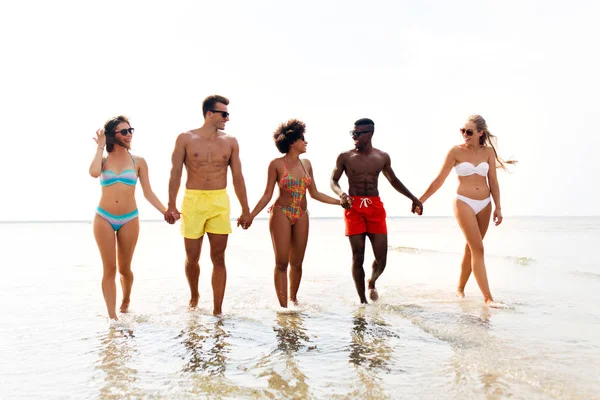 Mutlu arkadaşlar yaz plajı boyunca yürüyor. — Stok fotoğraf