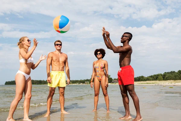 Друзья играют с пляжным мячом летом — стоковое фото