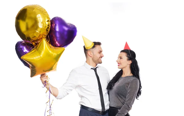 Happy couple with party caps and balloons — Stock Photo, Image