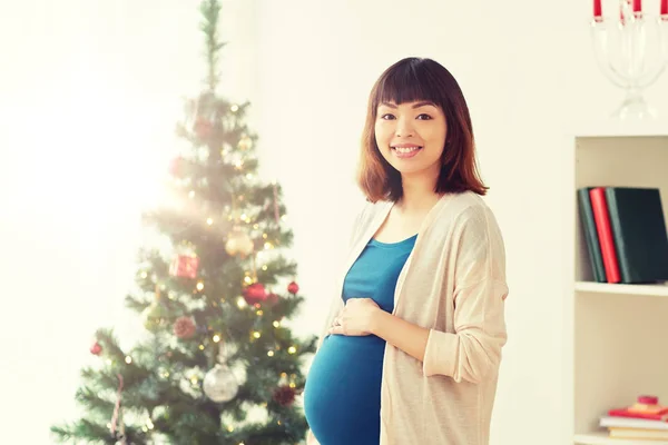 Mujer embarazada feliz en el árbol de Navidad en casa — Foto de Stock