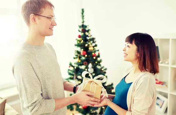 Муж дарит рождественский подарок беременной жене — стоковое фото