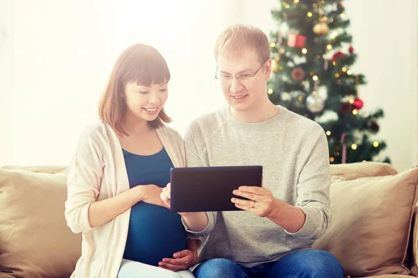 Uomo e moglie incinta con tablet pc a Natale — Foto Stock