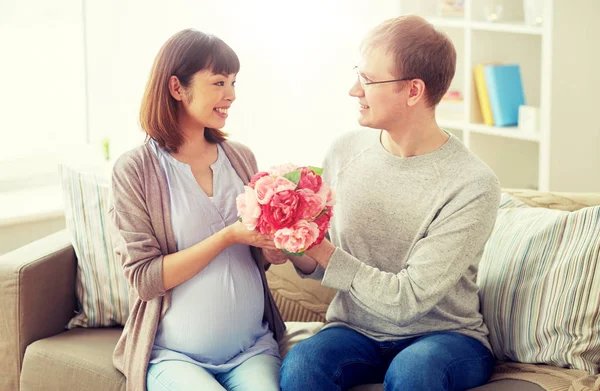 Happy husband giving flowers to his pregnant wife — Stock Photo, Image