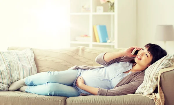 Šťastná těhotná žena volá na smartphone doma — Stock fotografie