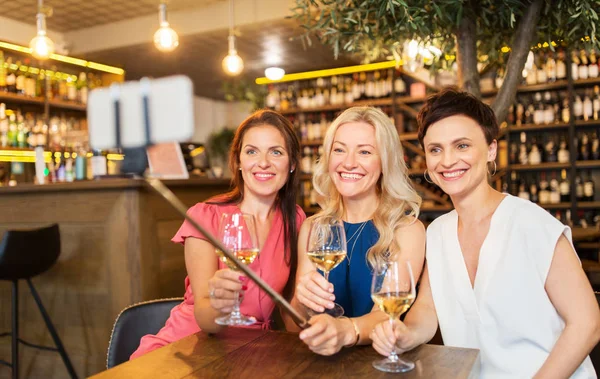 Женщины фотографируют селфи-палкой в винном баре — стоковое фото