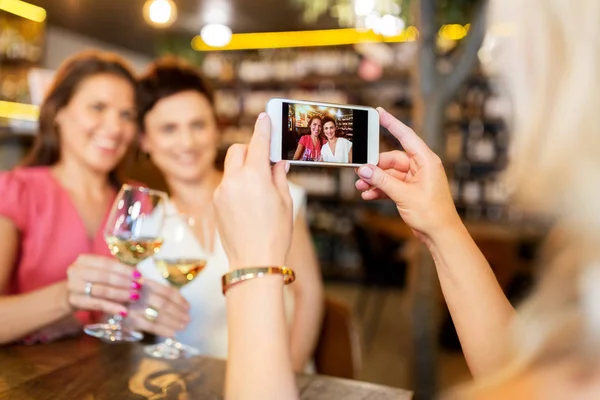 Žena zobrazující přátel pomocí smartphone na vinný bar — Stock fotografie