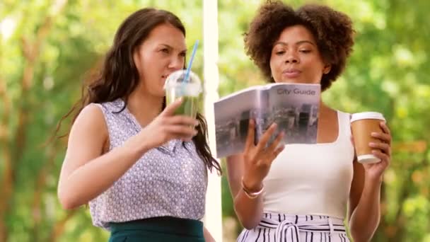 Kvinnor med city guide och drycker på gatan — Stockvideo