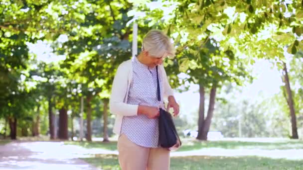 Старшая женщина звонит на смартфон в парке — стоковое видео