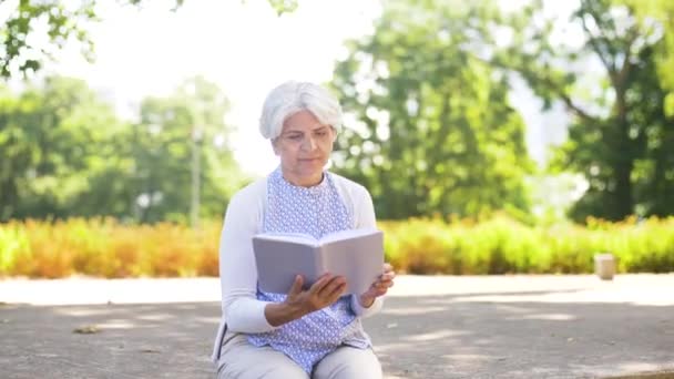 Senior kobieta czytanie książki na lato park — Wideo stockowe