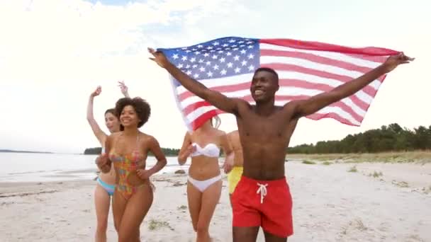 Freunde mit amerikanischer Flagge laufen am Sommerstrand — Stockvideo