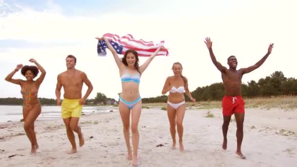 Freunde mit amerikanischer Flagge laufen am Sommerstrand — Stockvideo