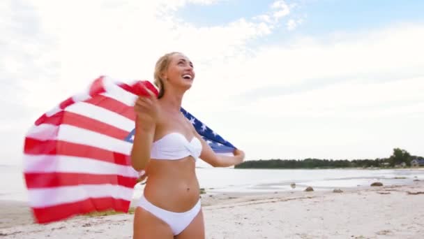 Щаслива молода жінка з американським прапором на пляжі — стокове відео