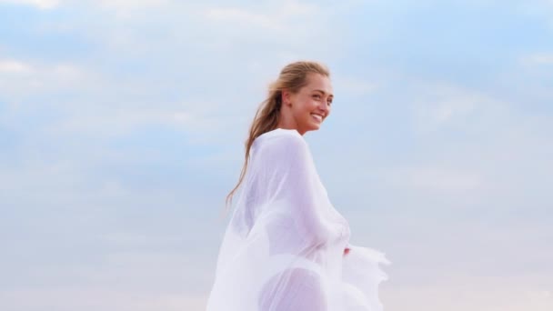 Felice donna con scialle che ondeggia nel vento sulla spiaggia — Video Stock
