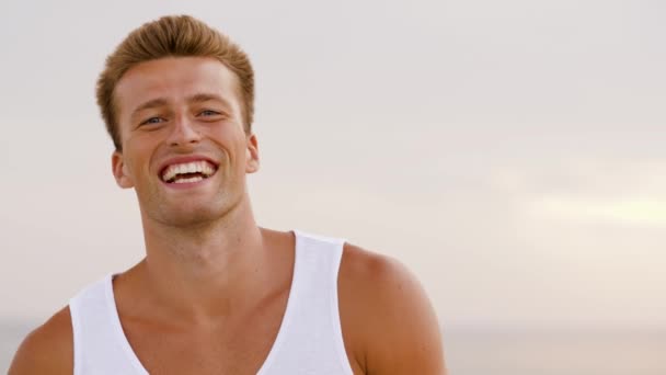 Портрет улыбающегося молодого человека на летнем пляже — стоковое видео