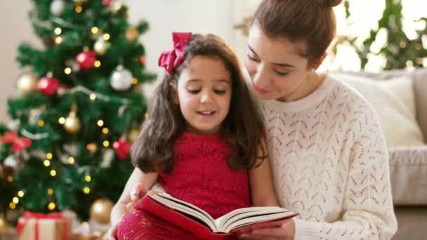 Mother and daughter reading book at christmas — Stock Video