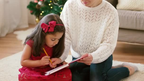 Mor och dotter med anteckningsboken vid jul — Stockvideo