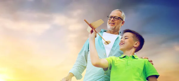 Старший мужчина и мальчик с игрушечным самолетом над небом — стоковое фото