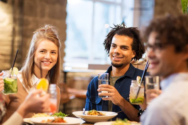 Счастливые друзья едят в баре или ресторане — стоковое фото