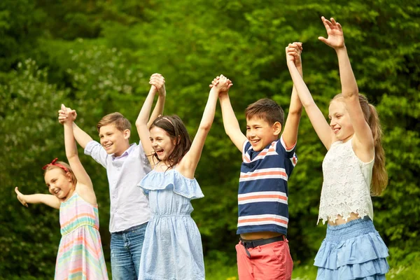 Niños felices sosteniendo las manos levantadas en el parque de verano —  Fotos de Stock