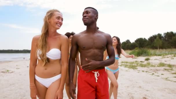 Smíšené rasy pár chůze podél pláže s přáteli — Stock video