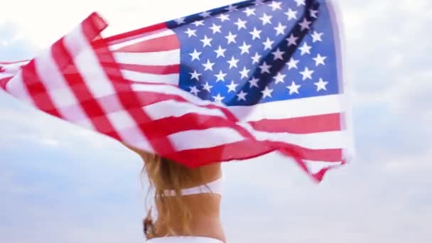 Щаслива молода жінка з американським прапором на пляжі — стокове відео