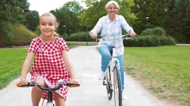 Бабушка и внучка катаются на велосипеде в парке — стоковое видео