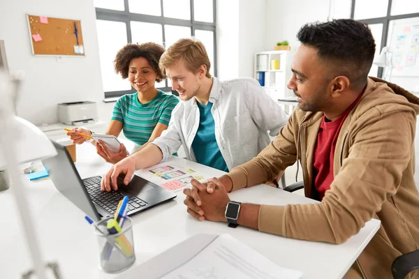 Lyckliga kreativa team med laptop som arbetar på kontor — Stockfoto