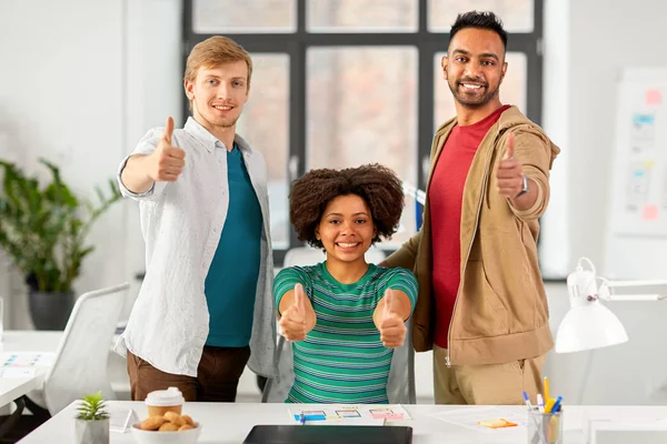 Lyckliga kreativa team visar tummen på kontoret — Stockfoto