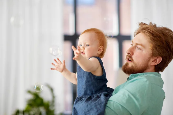 Padre e hija bebé con burbujas de jabón en casa — Foto de Stock