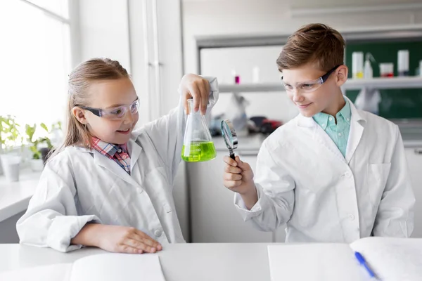 Niños con frasco y lupa en la clase de química — Foto de Stock