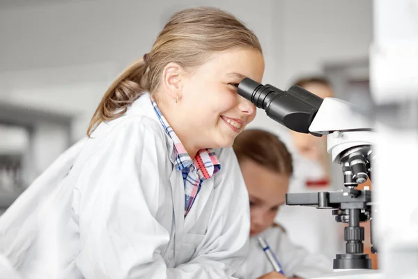 Niños o estudiantes con biología de microscopio en la escuela — Foto de Stock