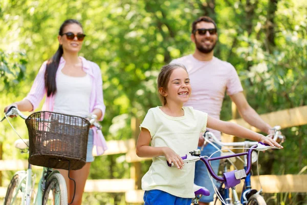 Счастливая семья с велосипедами в летнем парке — стоковое фото