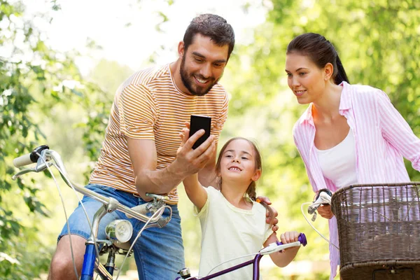 Rodziny ze smartfonem i rowery w lato park — Zdjęcie stockowe