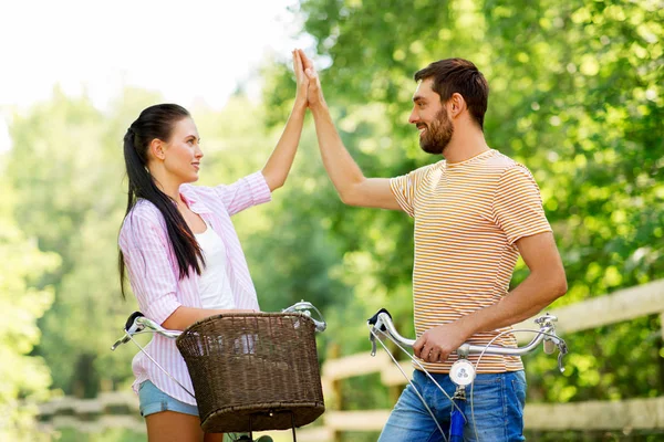Couple with bicycles making high five in summer — Stock Photo, Image