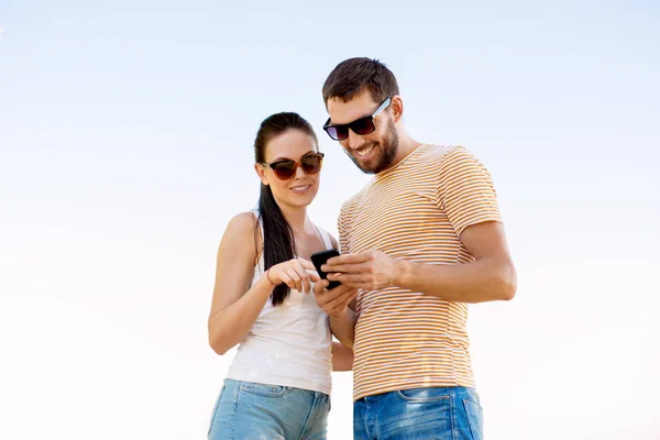 Happy couple with smartphone in summer — Stock Photo, Image