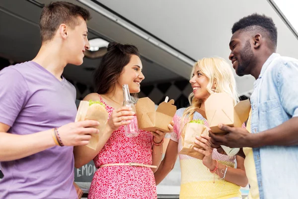 Amis heureux avec des boissons manger au camion de nourriture — Photo